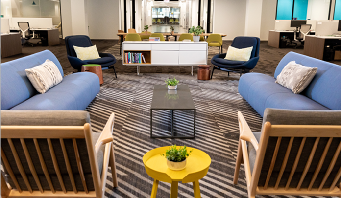 Les bureaux de Sprout Social à Chicago, avec un coin salon comprenant des canapés bleu clair, des fauteuils et des tables sur un tapis.​​ 
