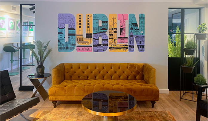 Les bureaux de Sprout Social à Dublin, avec un coin salon comprenant un canapé, deux petites tables basses et une fresque murale.​​ 