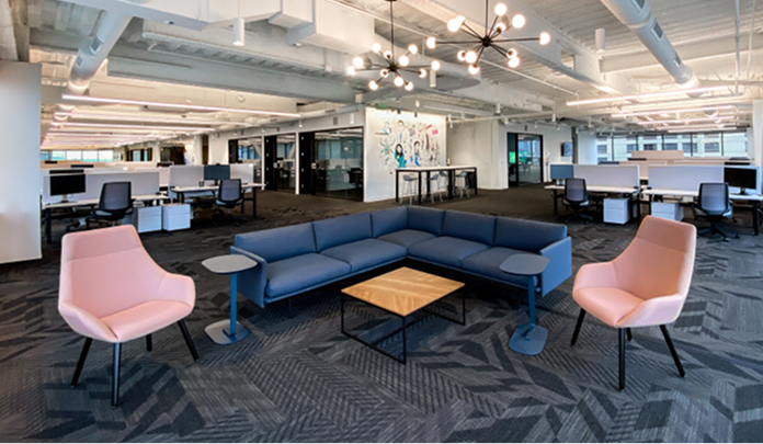 Les bureaux de Sprout Social à Seattle, un espace ouvert avec un grand canapé en forme de L, deux fauteuils et une table en bois.​​ 