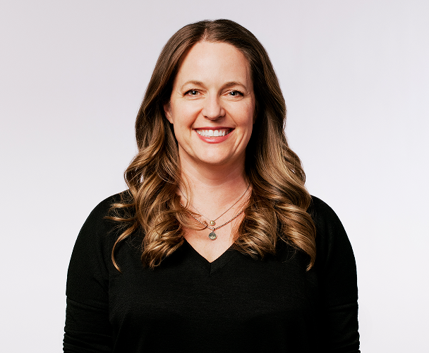 Portrait de Colleen Geiselhart, vice-présidente principale de l'expérience client, portant un haut noir.​​ 